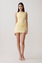 Woman wearing yellow draped mini dress.